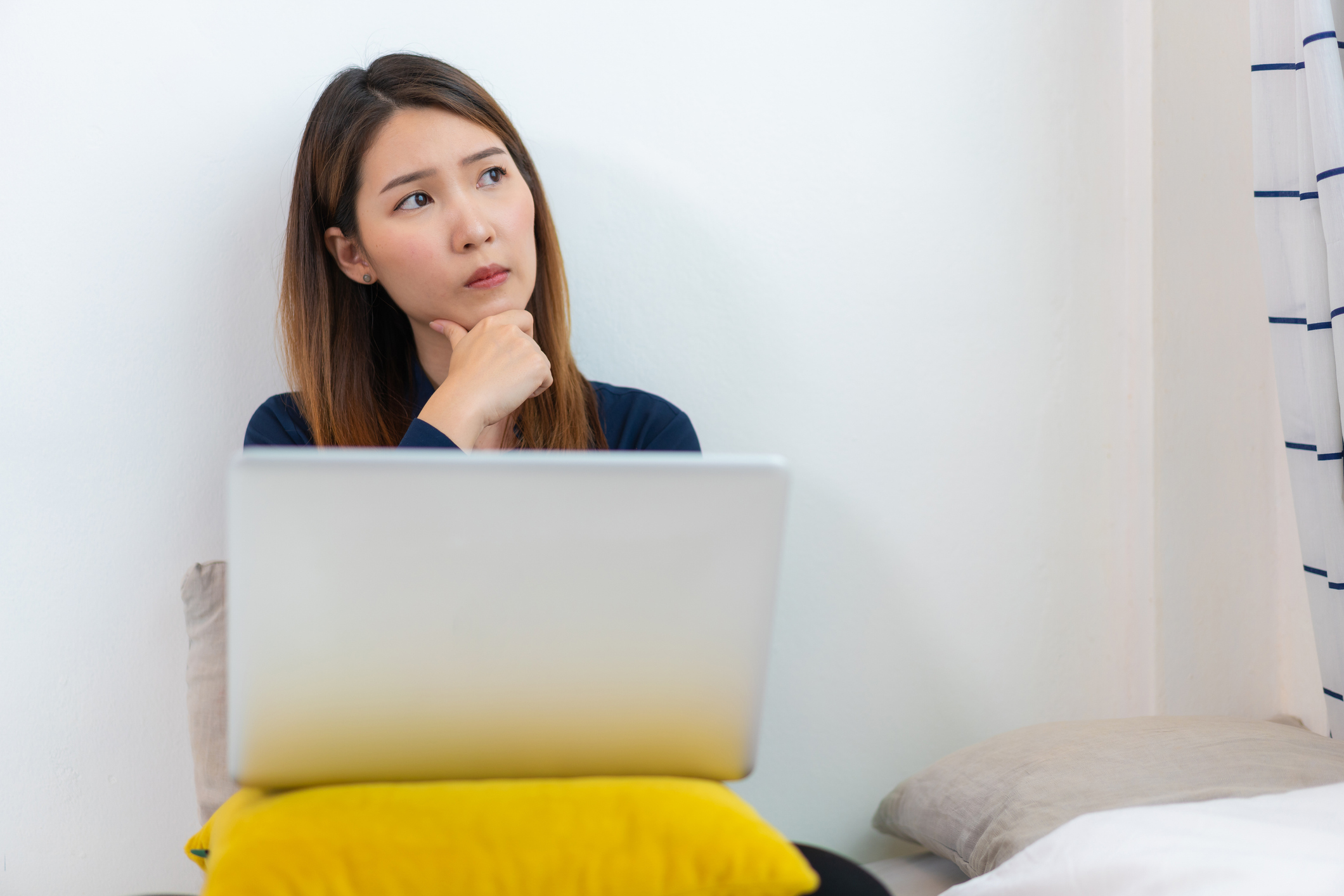 Concentrated Asian woman making decisions for her job working at home while coronavirus pandemic